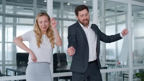 Deux partenaires commerciaux drôles et stupides, une femme et un homme, dansent et chantent au bureau, sur le lieu de travail, sans soucis