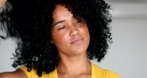 Woman Styles Curly Hair with Hands Indoors