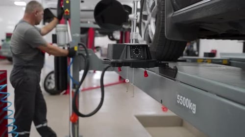 Auto Mechanic Aligns Car Wheels with Highprecision Equipment in Garage Expert Conducts Vehicle