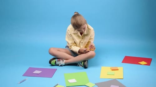 Young Girl Writing on Sticky Note on Floor