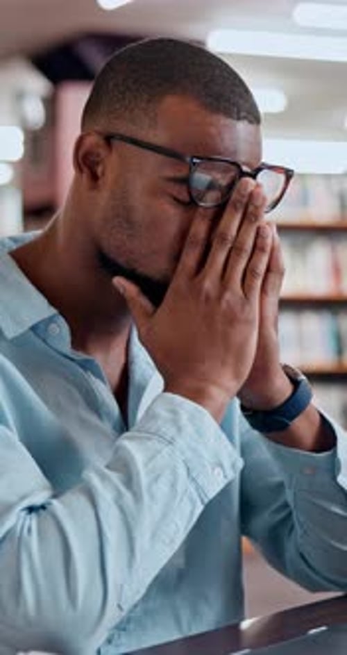 Man, student and stress in library with headache, eye strain and frustrated for exam