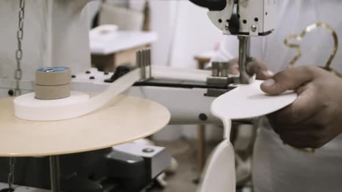 A man uses a sewing machine to stitch fabrics in a factory
