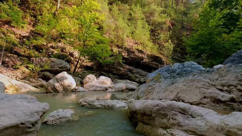 Rocky forest creek with small waterfall and turquoise water in peaceful nature view