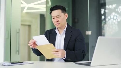 Man Reading Letter in Office Looks Upset