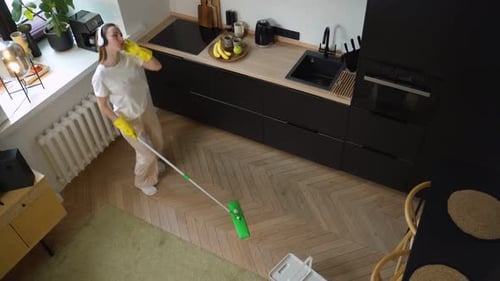 Woman Dances While Mopping the Kitchen Floor