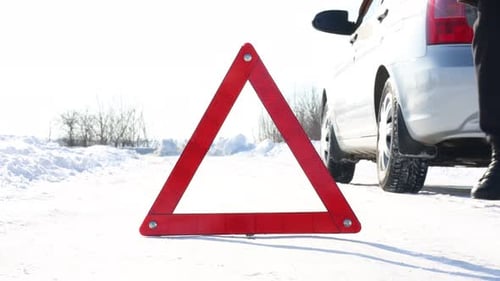 Man taking warning triangle near broken car from roadside at snowy winter, closeup. Space for text