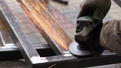 Sparks Flying as Worker Grinds Metal with Tool