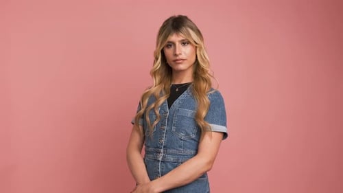 Femme transgenre confiante en robe en jean sur fond rose