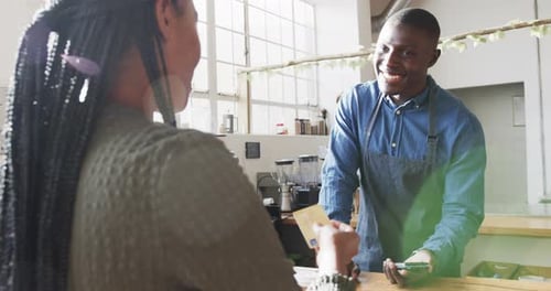 African american woman paying with credit card at coffee shop, slow motion