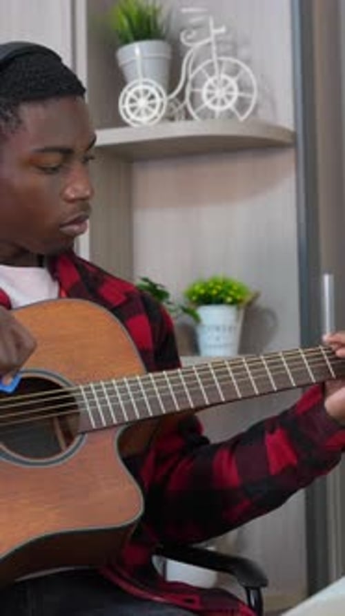 Young Adult Plays Acoustic Guitar Indoors