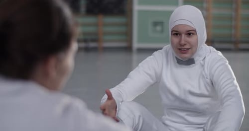 Muslim Fencer Speaking with Partner in Gym