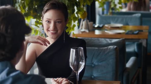 Woman Talking to Boyfriend during Date while Waiter Bringing Menu in Restaurant
