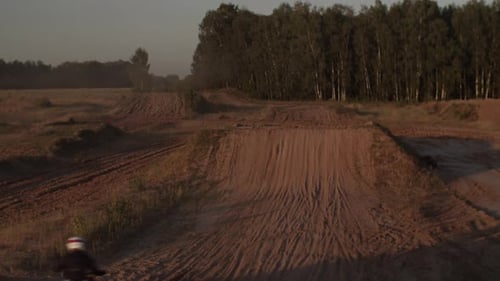 Dirt Bike Rider Jumping on a Rural Track at Sunset