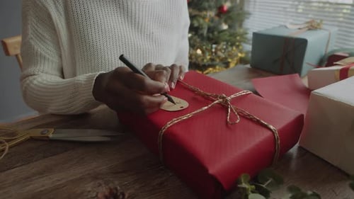 Woman Labeling a Beautifully Wrapped Christmas Present