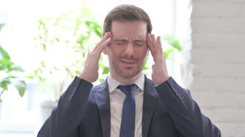 Portrait of Young Businessman with Headache in Office