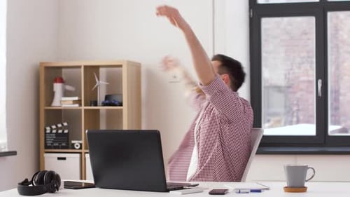 Excited man works on laptop at a desk