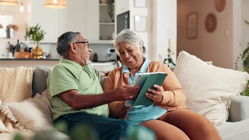 Senior Couple Laughing Together While Using Tablet