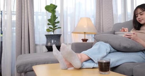 Woman Relaxing on Couch, Eating Chips