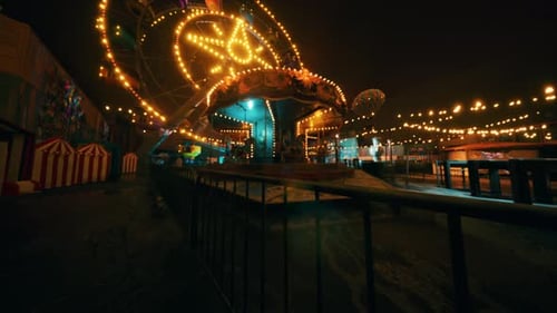 Empty Amusement Park at Night with Illuminated Rides and Quiet Atmosphere