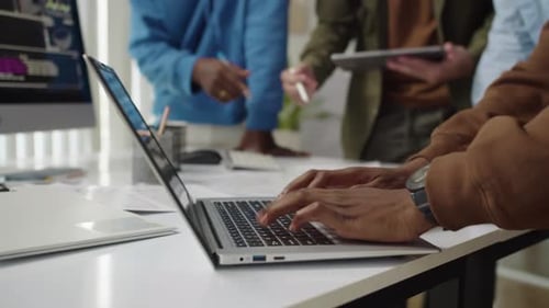 Unrecognizable Developer Coding on Laptop when Meeting with Team at Office