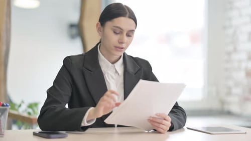 Elegant Woman Reviews Documents in Bright Office
