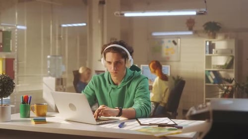 Young Adult Works on Laptop in Open Office