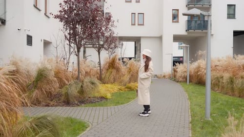 Impatient woman waiting for a late friend outside an apartment building.