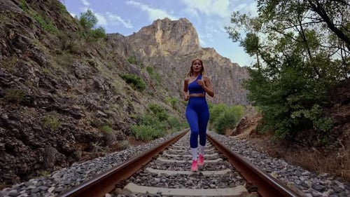 Woman Running on Railroad Tracks