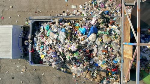 Drone view of a truck is being loaded with garbage through a funnel at waste sorting plant. Slow mot