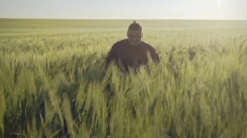 Person Walks Through Green Crops in Rural Field