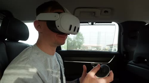 Junger Mann mit Virtual-Reality-Brille in weißer Farbe spielt Spiele oder surft auf dem Rücksitz im Internet