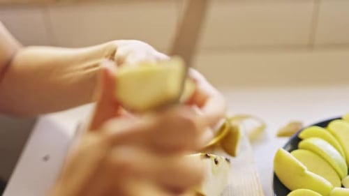 Woman Peeling and Slicing Green Apples on Wooden Cutting Board