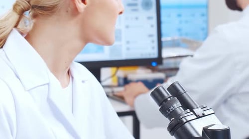 Woman scientist looking into microscope in lab