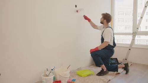 Young Adult Painting a Wall with Paint Roller