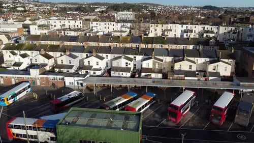 A rising shot of a bus station, revealing a small city behind in the distance.
