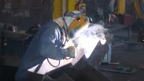 Metal Worker Welding With Sparks in a Workshop