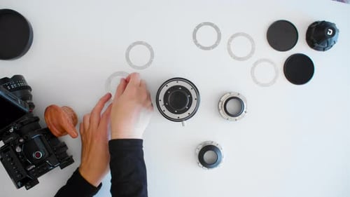 Hände eines jungen Mannes beim Auswechseln von Metallscheiben, Halterungen an einer Videografie, Video, Kino, Kinoobjektiv, Kamera für