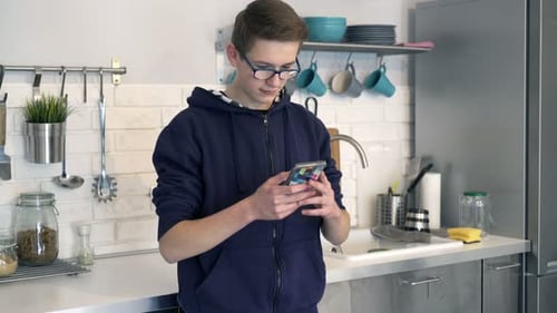 Teenage Boy Using Phone in Kitchen at Home