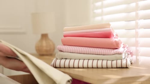 Woman putting clothes into drawer of cabinet indoors, closeup