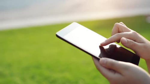 4k-Videomaterial einer unkenntlichen Frau, die ein Smartphone in einem Park benutzt