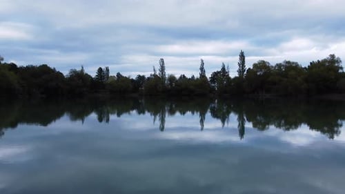 Aerial Footage of a Green Lake with a Reflection of Clouds and Trees