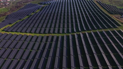 Solar panels cover a large field in sunlight during midday hours