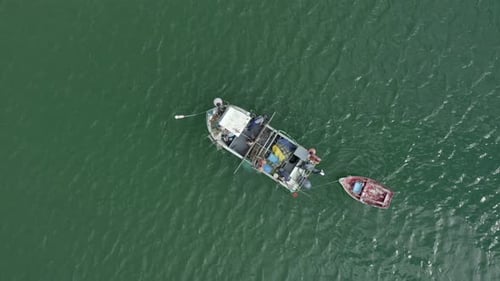 Fischer arbeiten auf einem kleinen Fischerboot im grünen Wasser von Salema, Portugal