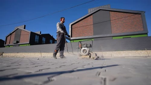 Travailleur utilisant un compacteur à plaques sur une chaussée résidentielle