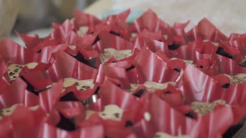 Close-up of a pastry chef pouring batter into cupcake liners for baking.
