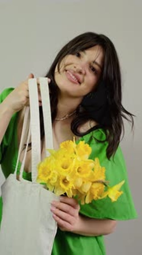 La mujer lleva una bolsa con ramo, narcisos amarillos en el interior, entrega de flores a domicilio para celebraciones, énfasis