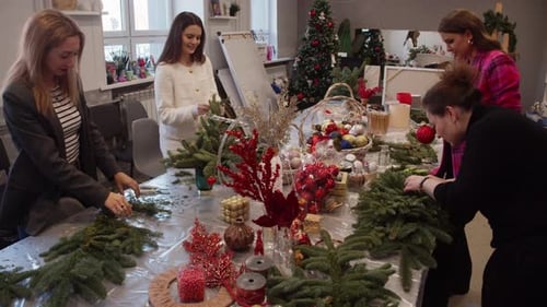 Women Decorating Christmas Trees Together at Festive Gathering