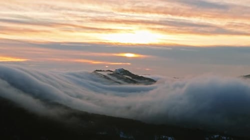 Goldene Wolken über nebligen Berggipfeln