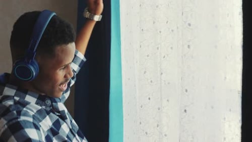 Young Man Enjoys Music Indoors by Window