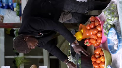 A Vendor Showcasing Their Goods at a Market in Africa - Vertical Shot